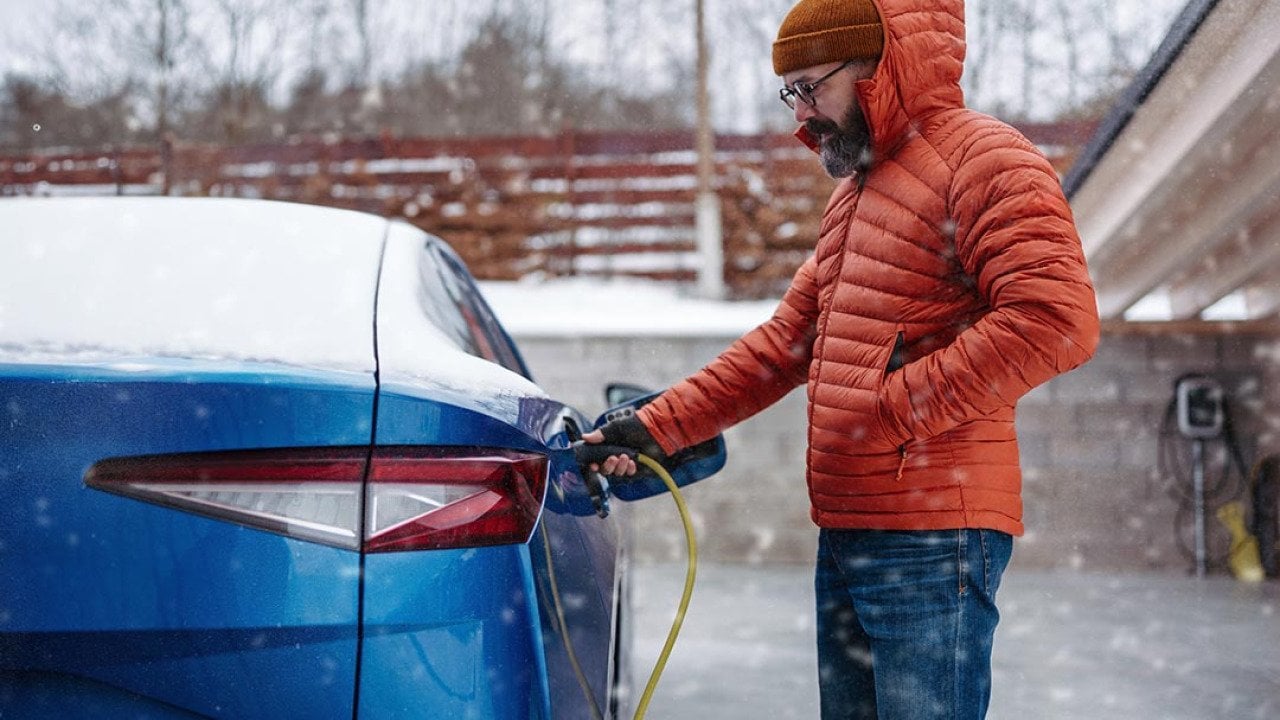 A man charging his EV during a snowy day.