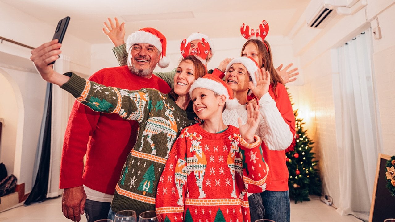 A six-member family in their Christmas hats and outfits squeezing in for a selfie.