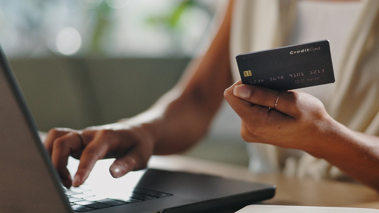 A female business professional typing credit card information for a purchase using her laptop.