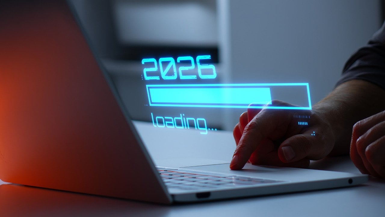A person's hand interacting with a laptop illustrated with a holographic '2026 loading' graphic.
