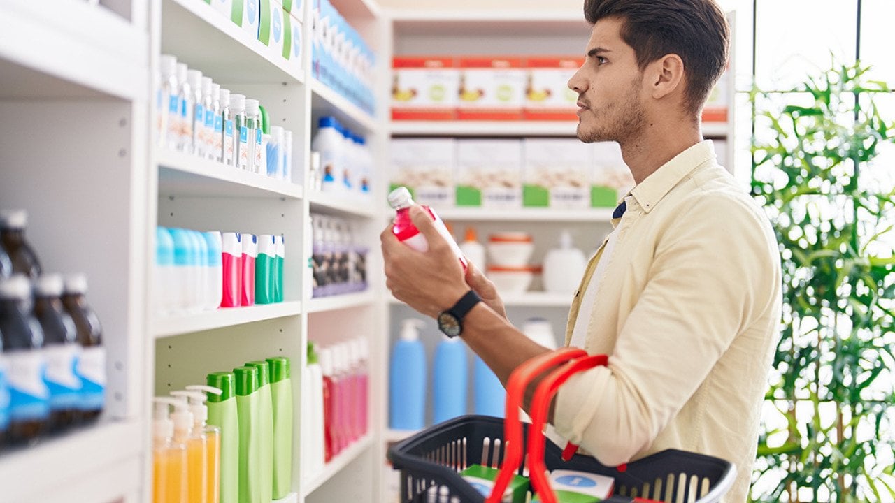 A man holding a basket and shopping at a pharmacy.