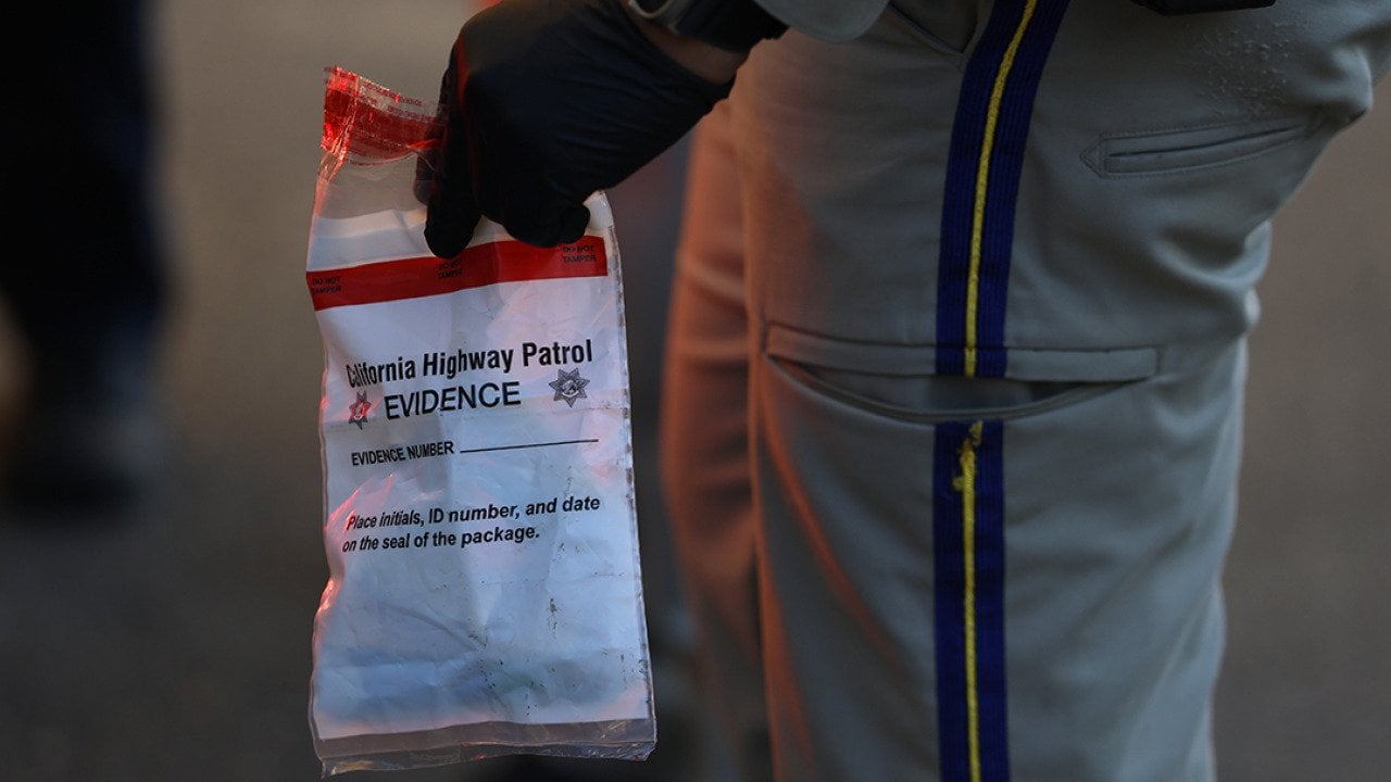 A California Highway Patrol officer holding an evidence bag after taking a suspect into custody.