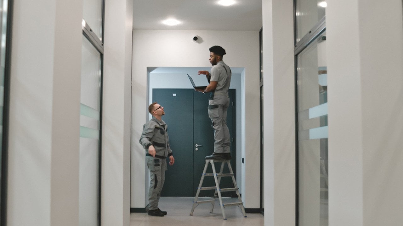 Two installation workers setting up a surveillance camera.