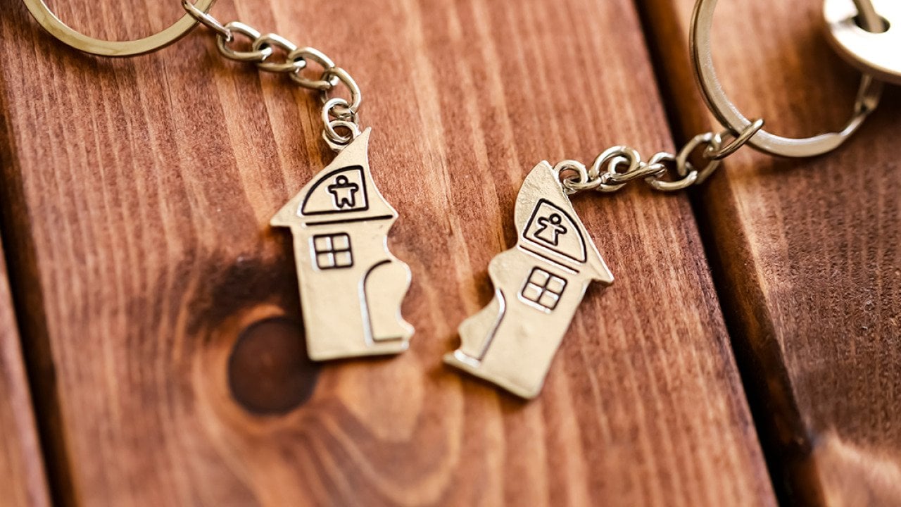 Two halves of a home keyholders as a concept of property sale after divorce.