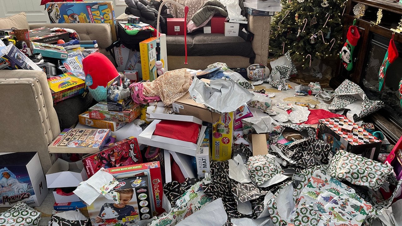 Piles of messy packaging and opened presents in a living room during Christmas morning.