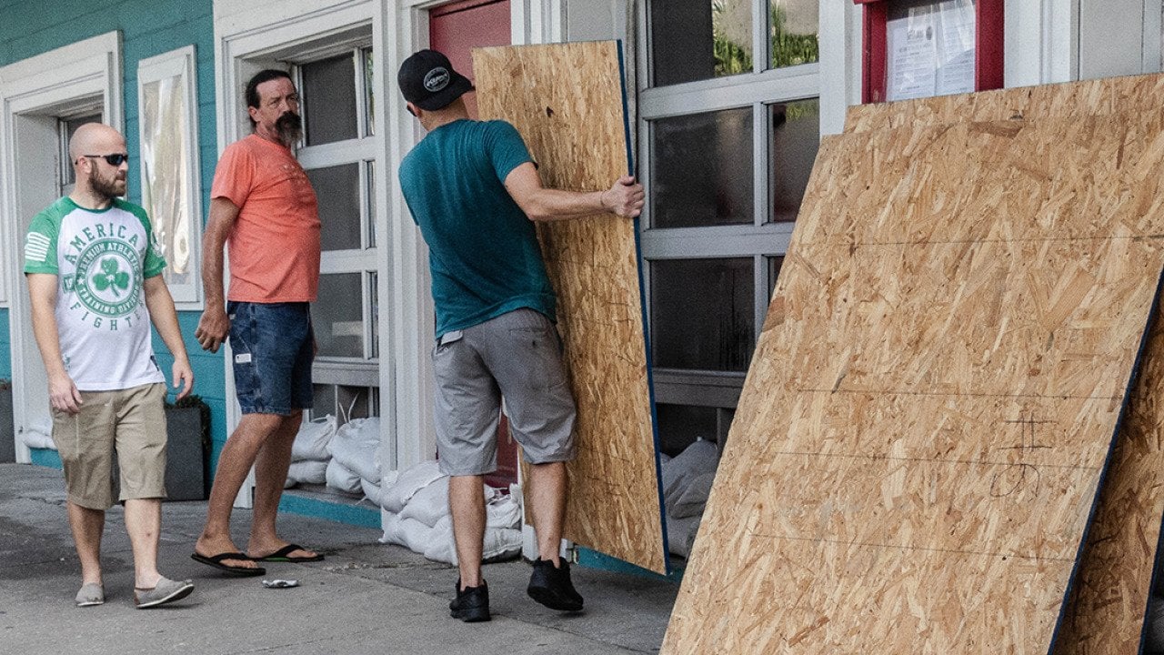 A group of workers board restaurant windows in preparation for a hurricane.