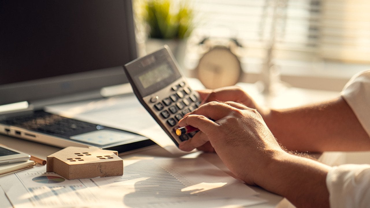 A real estate professional using a calculator over tax documents.