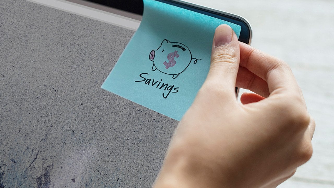 A person sticking a savings note on a computer screen.