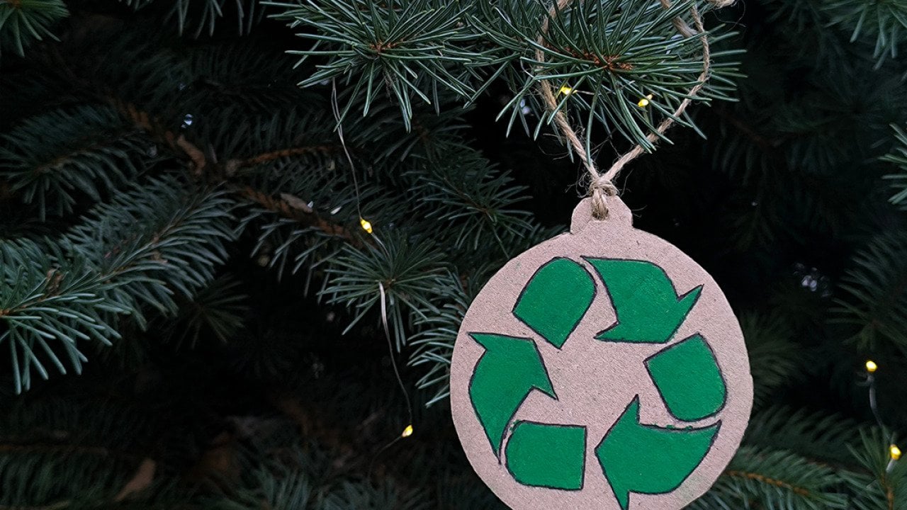 A recycling symbol ornament on a Christmas tree.
