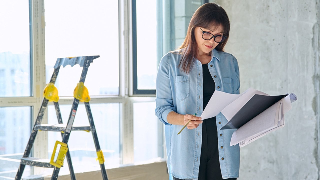 A female interior designer reviewing an apartment renovation plan.