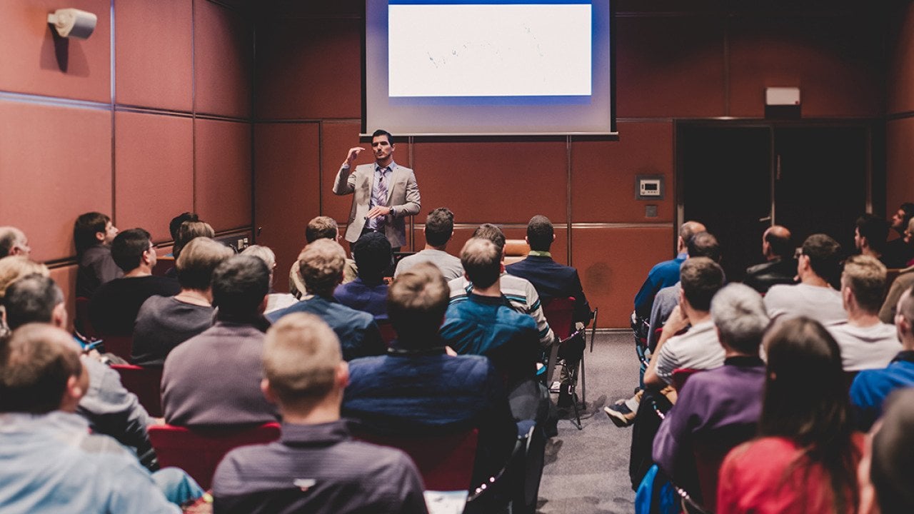 An audience in a conference room listening to a speaker.