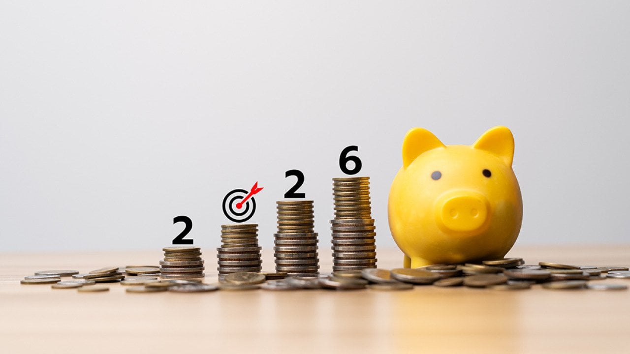 2026 target savings represented by a yellow piggy bank and a row of stacked coins.