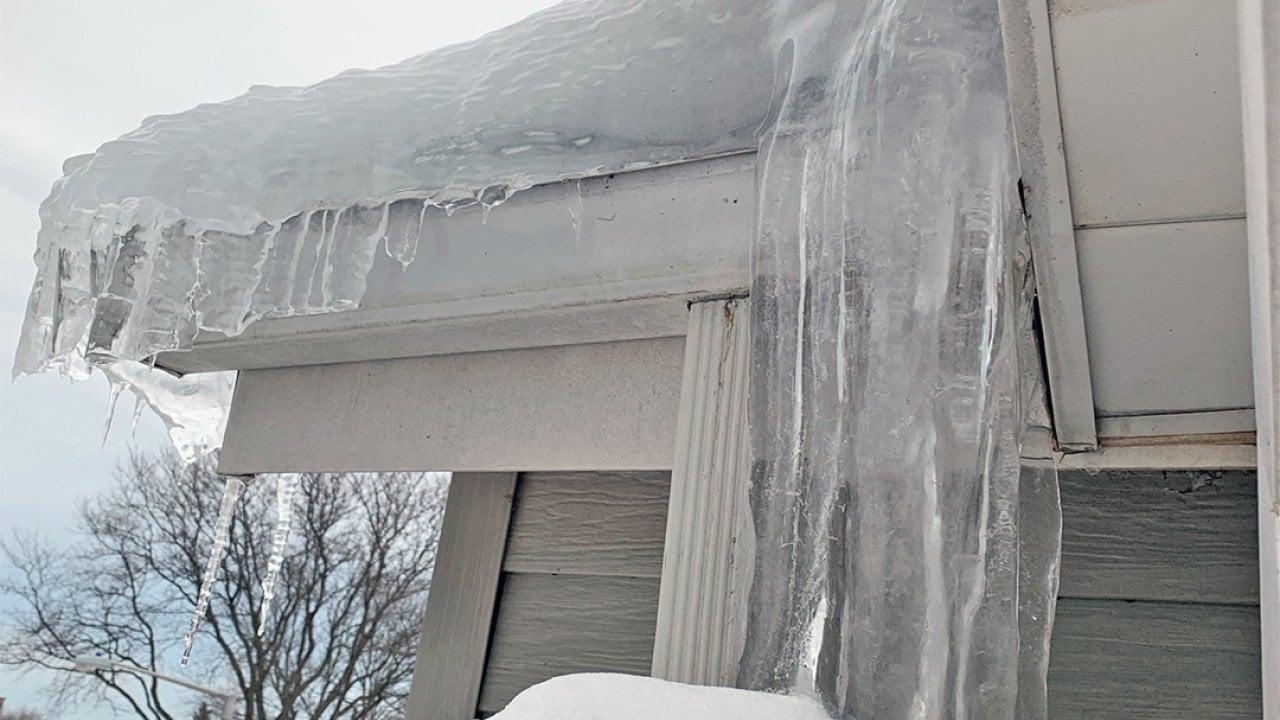 Thick ice dam formed on a house's roof.