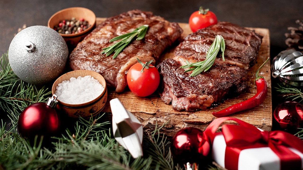 Beautifully grilled ribeye steaks prepared on a wooden board for Christmas.