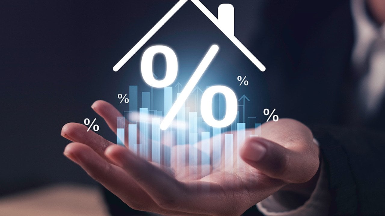 A real estate agent's hand holding up a hologram of a home with percentage figure.