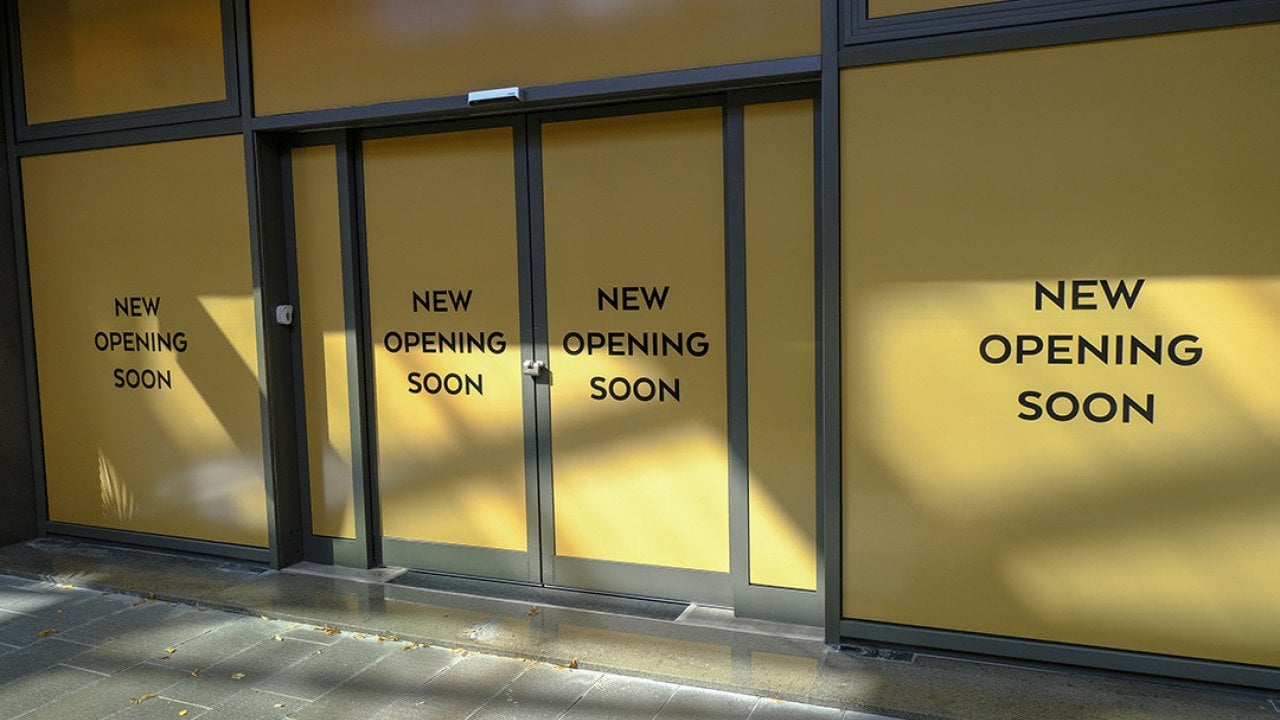 Entrance of a new retail store with 'opening soon' signs.