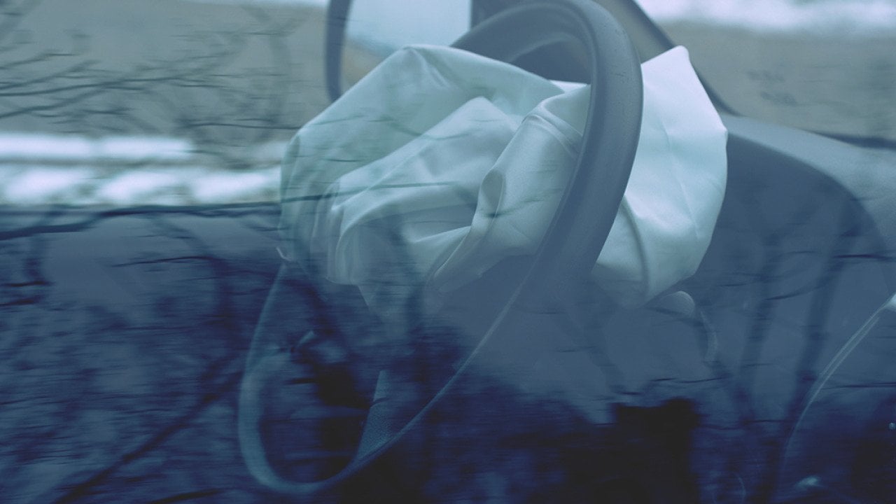 A car's steering wheel with a deployed airbag.