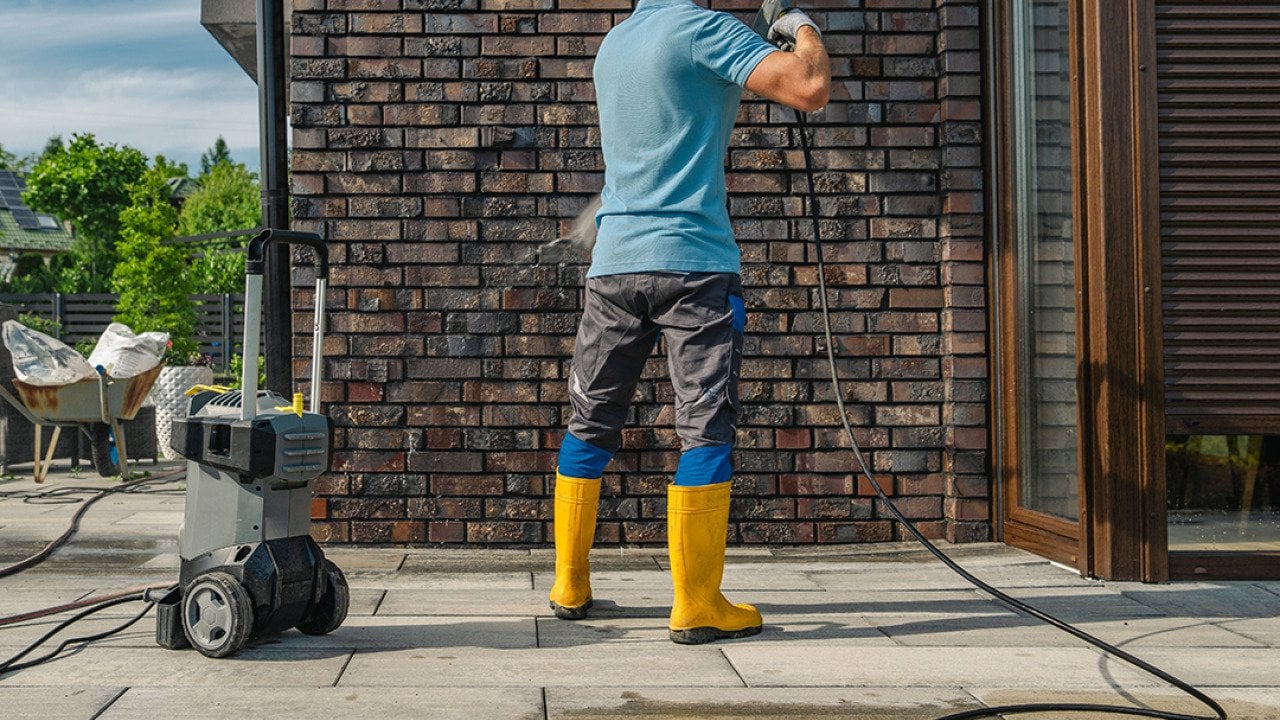 A pressure wash cleaner working on a dirty brick wall.