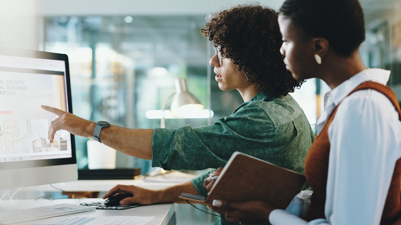 Two coworkers collaborating on a task in their office.