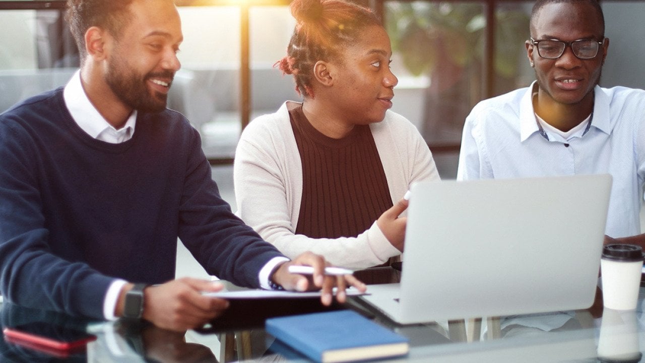Three members of a business team brainstorming on strategy in an office.