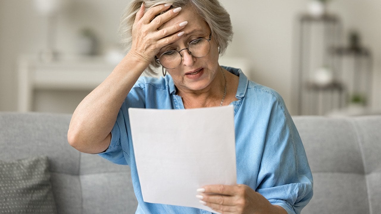 A frustrated senior woman reading a document at home.