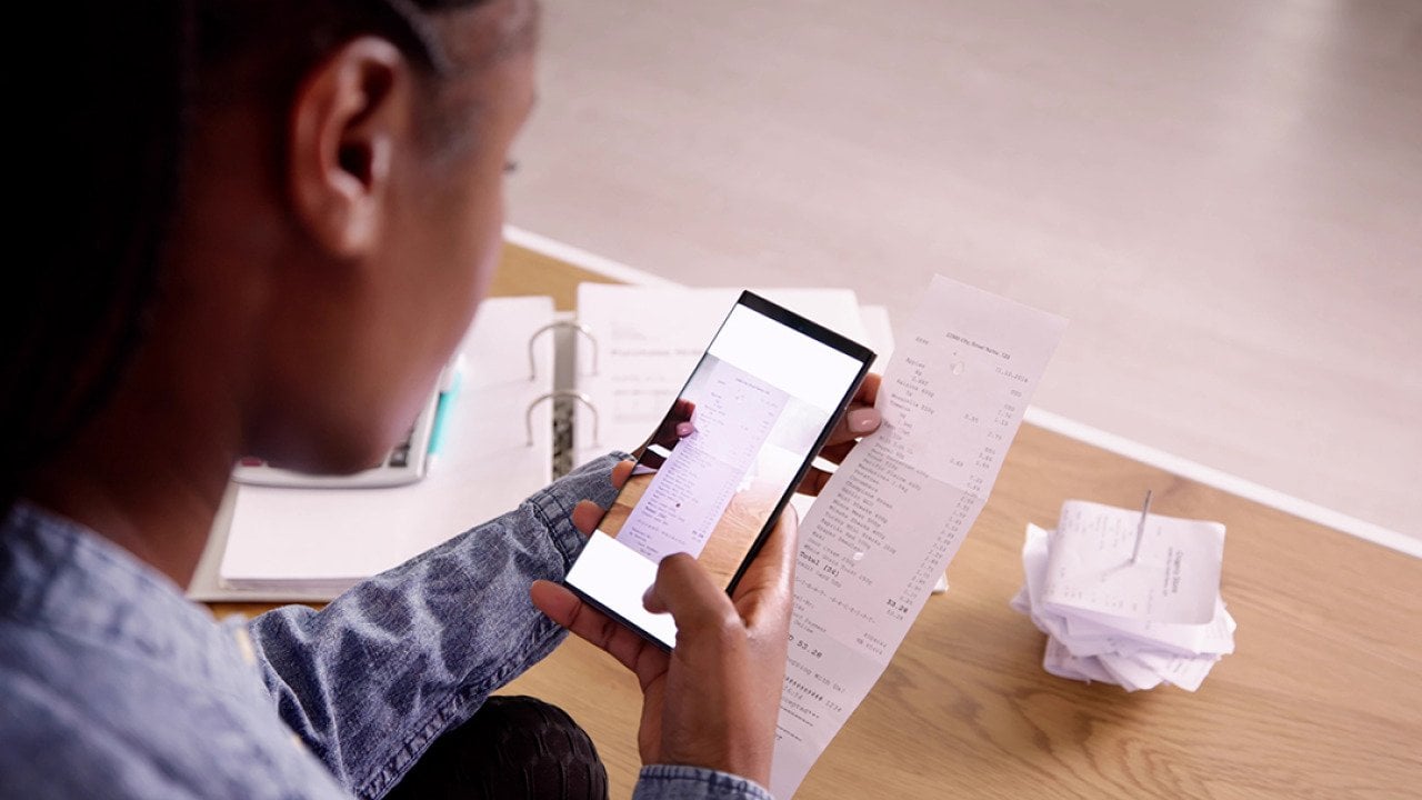 A woman taking a photo of a receipt using her phone.