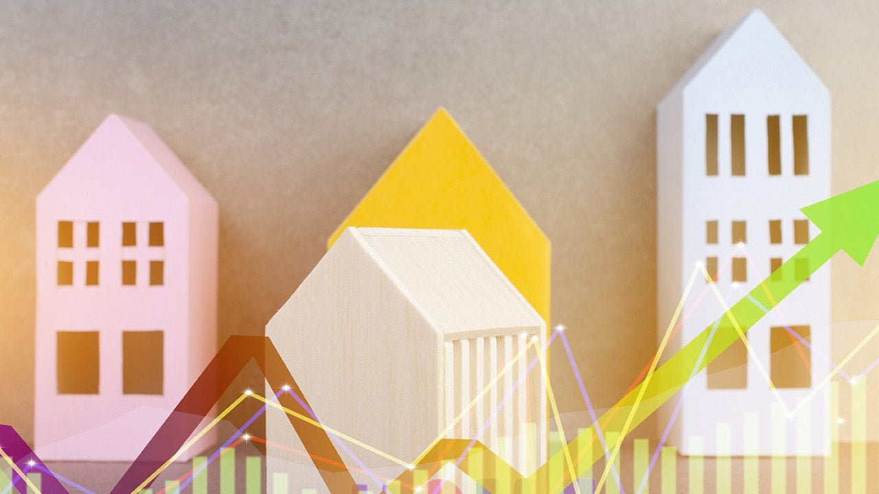 Colorful wooden figures of homes illustrated with finance chart graphics.