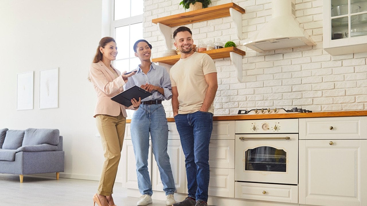 A female broker giving a young couple a tour of a house.