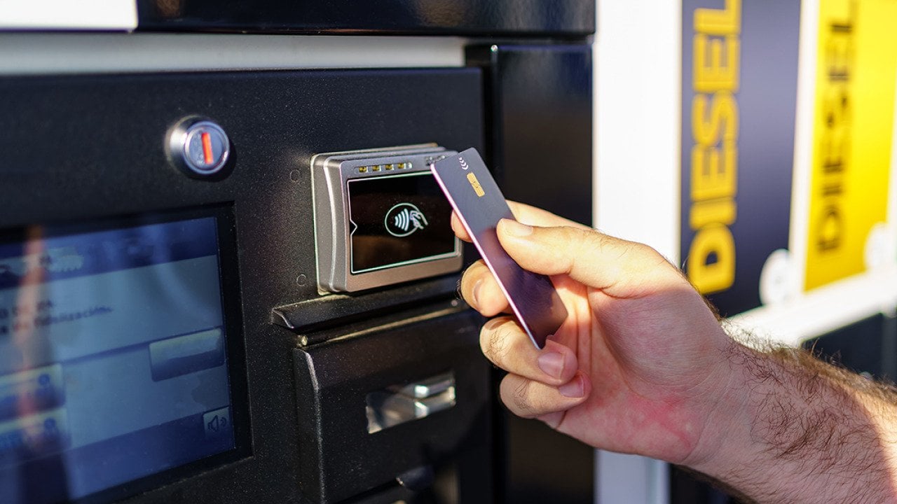 Hand of a person paying using card by the fuel pump at a gas station.