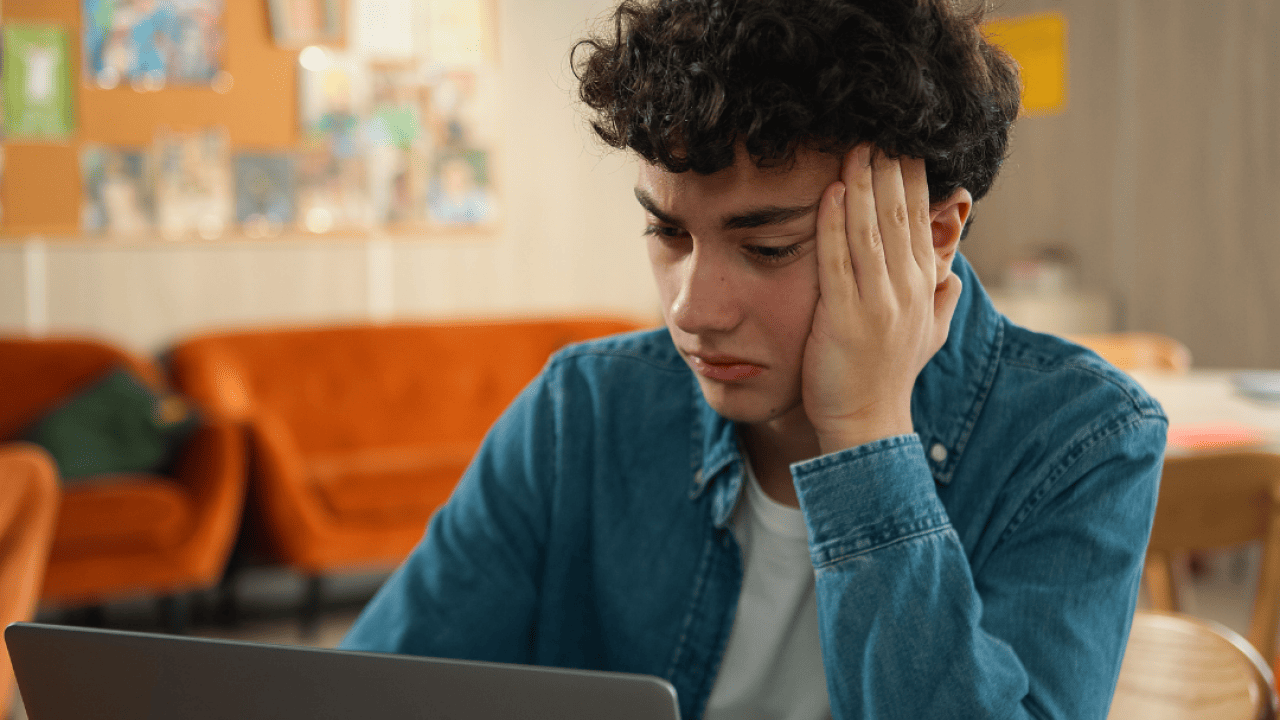 A stressed young adult sitting in front of a laptop. 