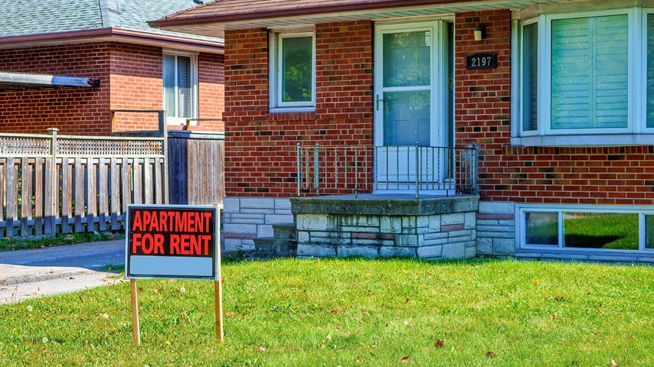 An 'apartment for rent' sign on a house lawn.