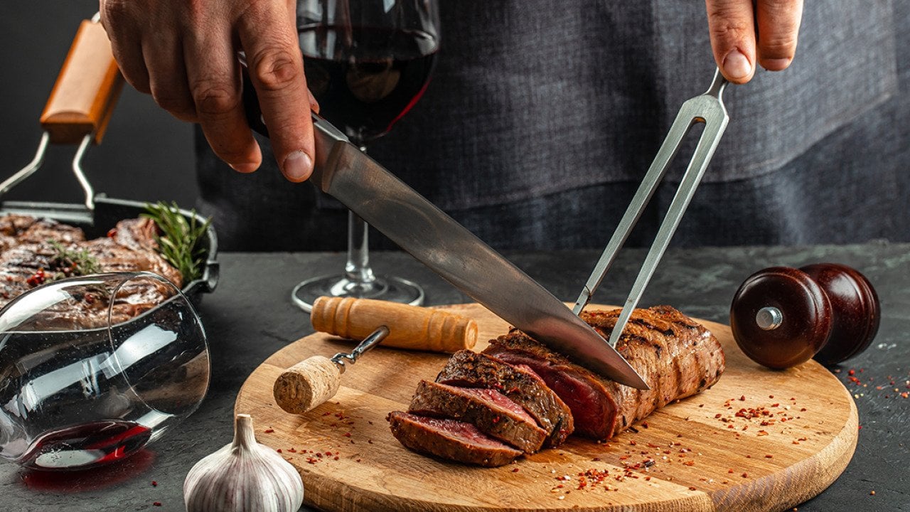 Grilled steak on a wooden cutting board and a glass of red wine.