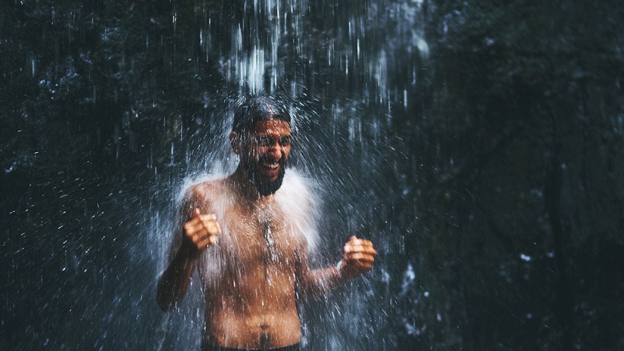 A man under a cold waterfall shower.