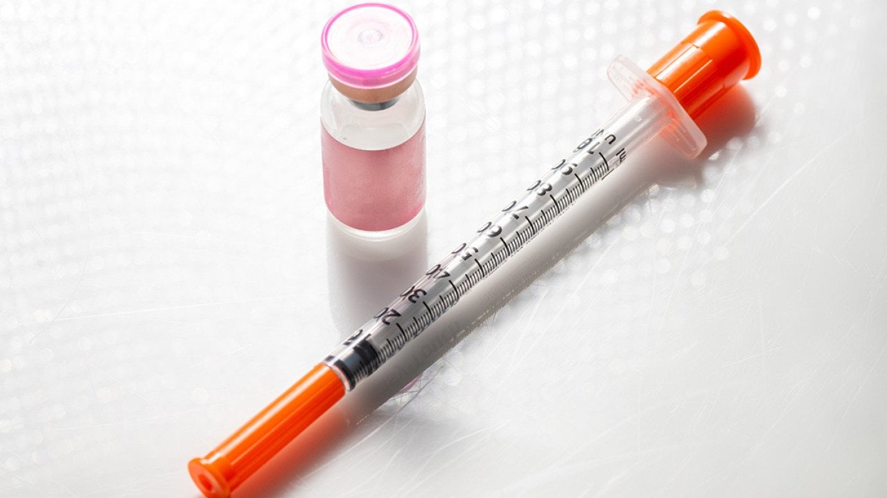 A vial with injectable compound and a syringe.