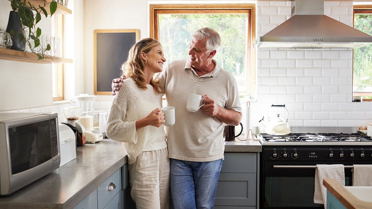A middle-aged couple having a coffee in their kitchen.