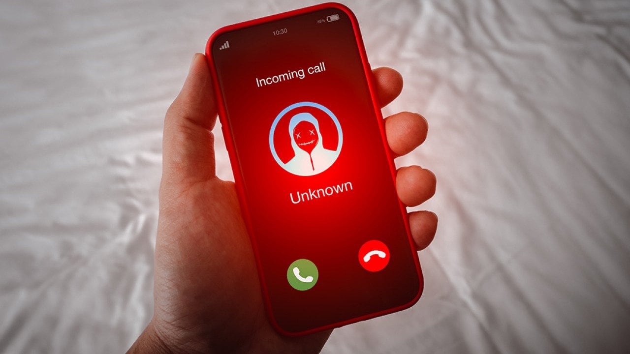 A person's smartphone receiving an unknown call with a red alert.