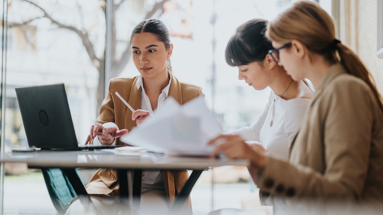 A group of three female professionals in a coworking space.