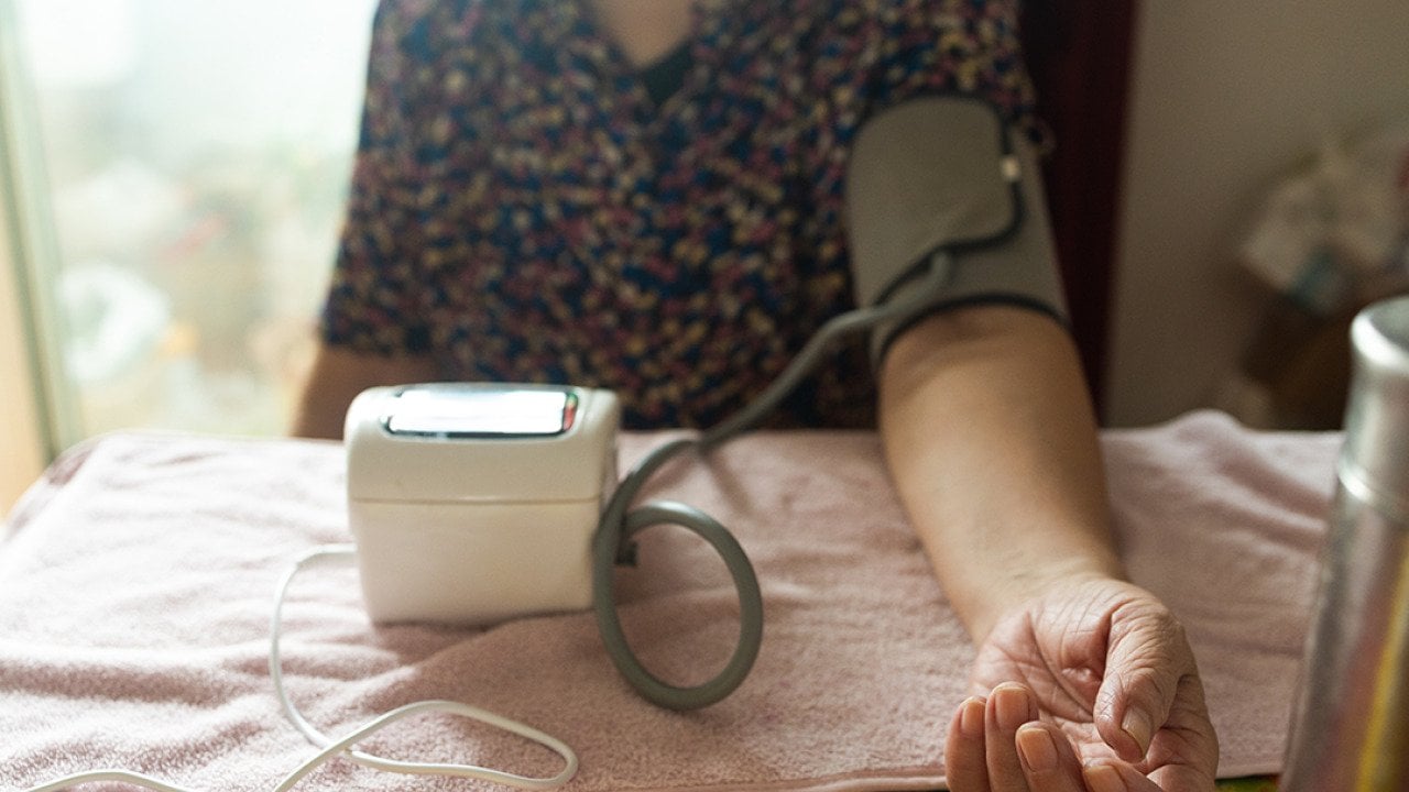 A senior woman getting her blood pressure checked using a digital monitor.