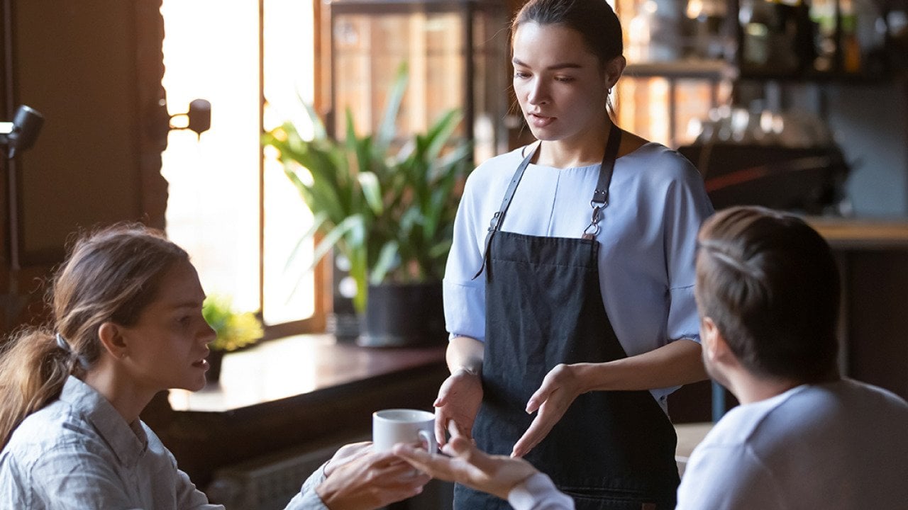 An angry couple disputing a complaint with a cafe waitress.