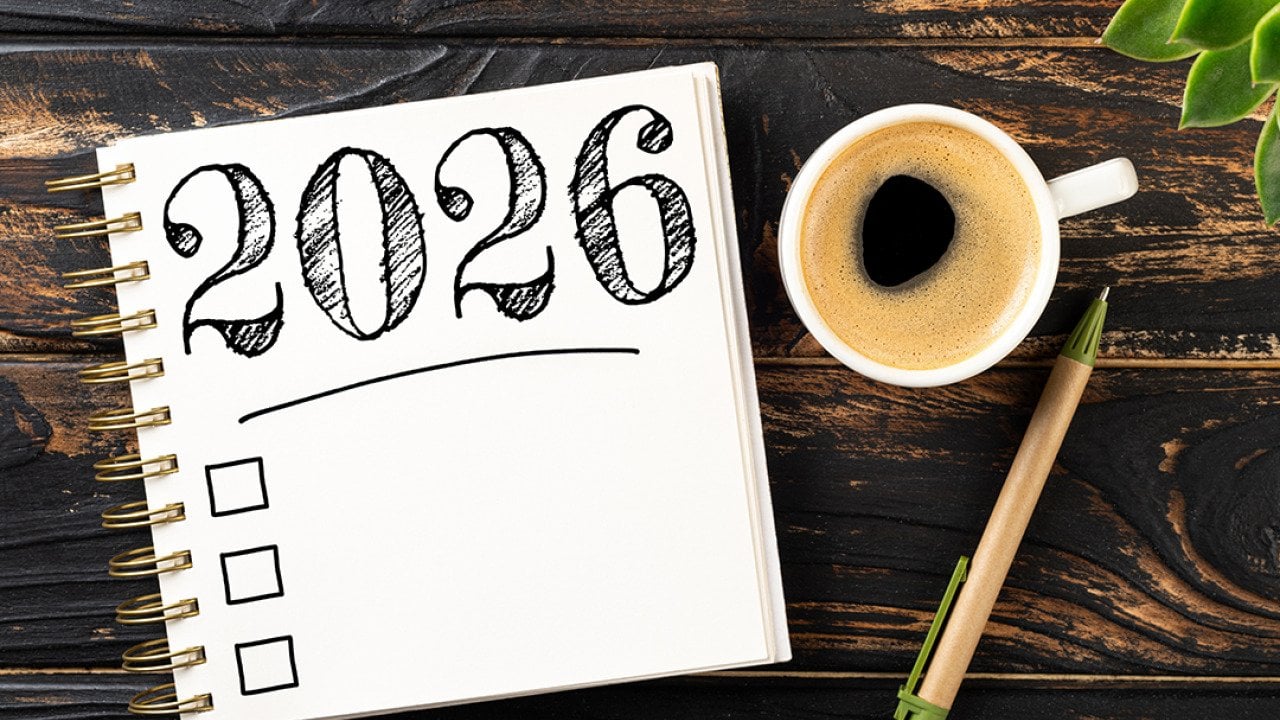 A notebook with a 2026 checkbox with a pen and a cup of coffee on a desk.
