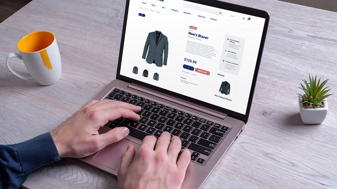 Person using a laptop to shop for men's blazer online.