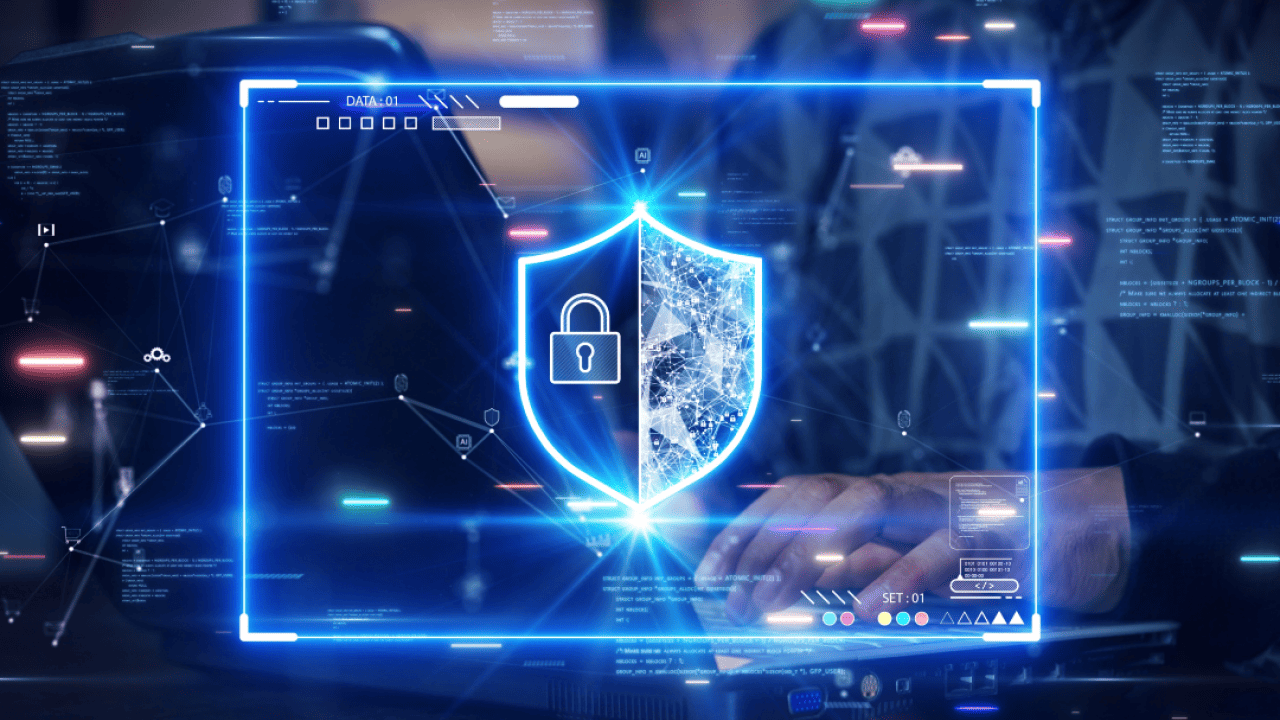 A person's hands type on a computer keyboard with a glowing security shield overlaid on the photo.