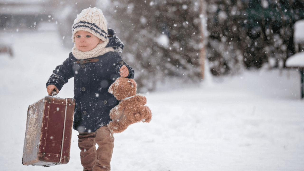 Baby playing with teddy bear in the snow.