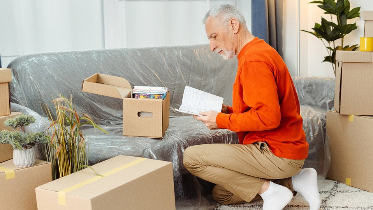 A senior man unpacking boxes of belongings when moving to a new home.