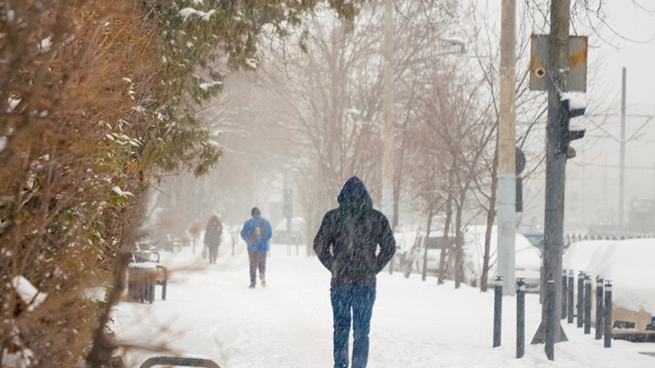 People walking through sidewalks during a heavy snowfall day.