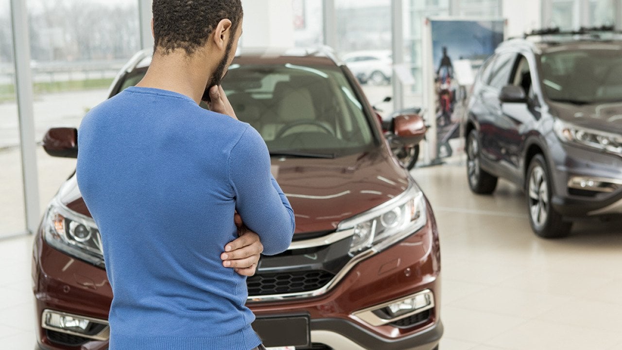 Stražnji pogled na čovjeka koji bira automobil u prodajnom salonu.