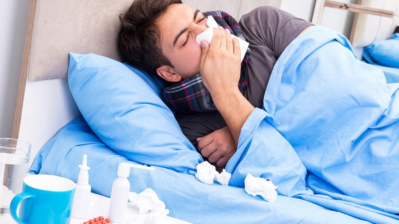 A sick man with flu lying in bed.