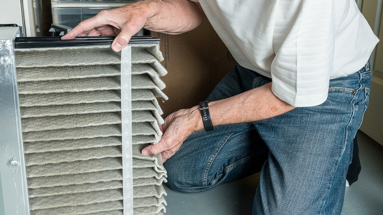 Man changing a folded dirty air filter of an HVAC system.