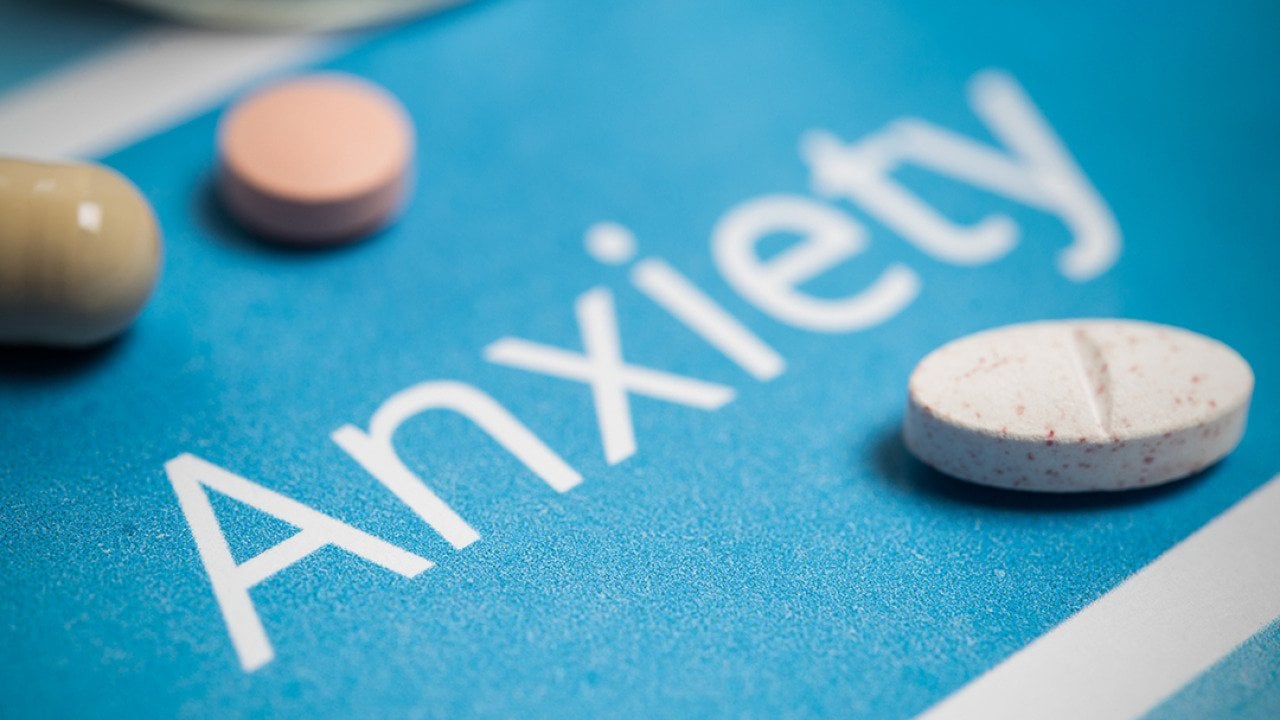 Medication and pills on top of a surface with the word 'anxiety'.