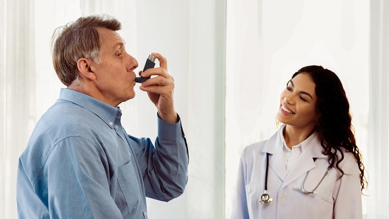 A female doctor monitoring her senior patient in taking an asthma inhaler.